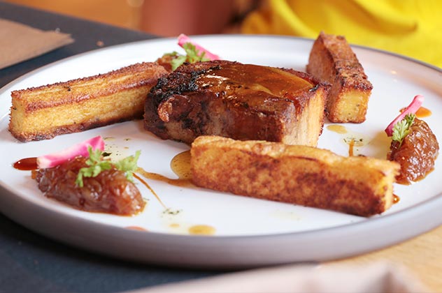 Poitrine de porc marinée puis grillée, confit d’échalotes au miel, frites de polenta à la sarriette